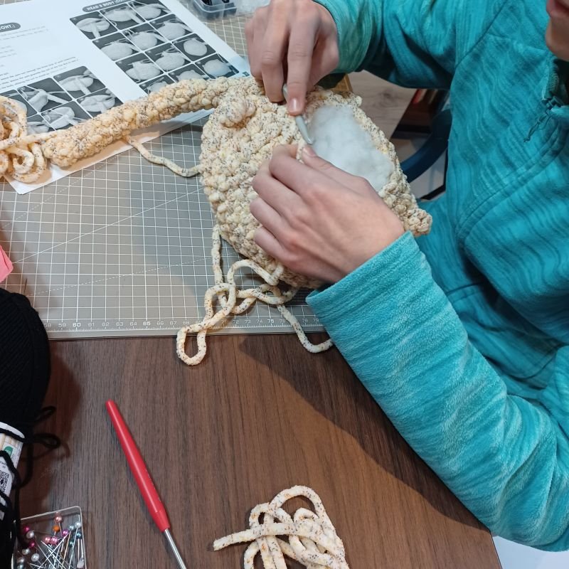 élève adolescente pendant un cours de crochet où elle réalise un chat en amigurumi