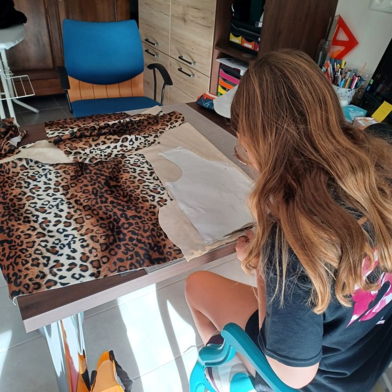 enfant en train de découper son gilet sans manches dans de la fausse fourrure léopard